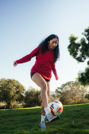 Female soccer player kicking a soccer ball.