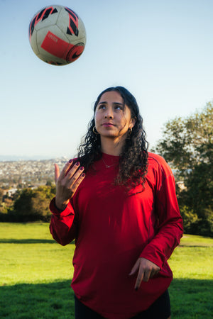 Female soccer player tossing a soccer ball in the air.