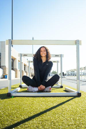 Brinley Campbell, Division 1 Track and Field Star posing under the hurdles.
