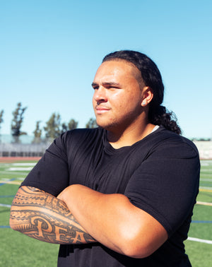 Division one football player standing with arms crossed.