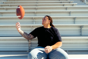 Division 1 Football player tossing football in the bleachers.