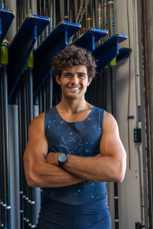 Rex Bales, Captain of the USD Rowing team, in front of a rack of oars.