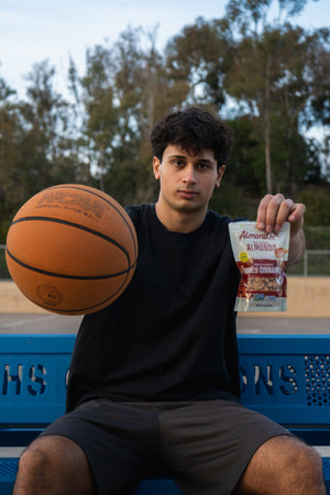 Division 1 basketball player on bench with ball and bag of almonds.
